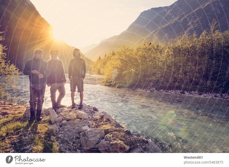 Slowenien, Bovec, drei Freunde am Fluss Soca bei Sonnenuntergang Fluesse Fluß Flüsse Mann Männer männlich stehen stehend steht Gewässer Wasser Erwachsener