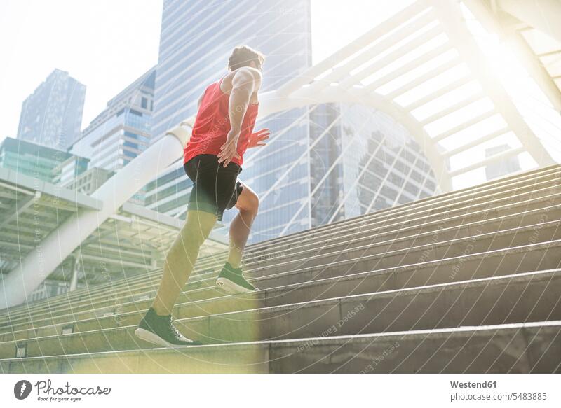 Mann im roten Fitnesshemd rennt in der Stadt die Treppe hinauf aufwärmen sich aufwärmen sich aufwaermen Läufer Laeufer aufwärts nach oben laufen rennen Jogger