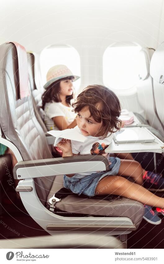 Zwei kleine Mädchen fliegen im Flugzeug und spielen mit Papierflieger Papierflugzeug weiblich Schwester Schwestern Ferien Urlaub fliegend Flieger Flugzeuge