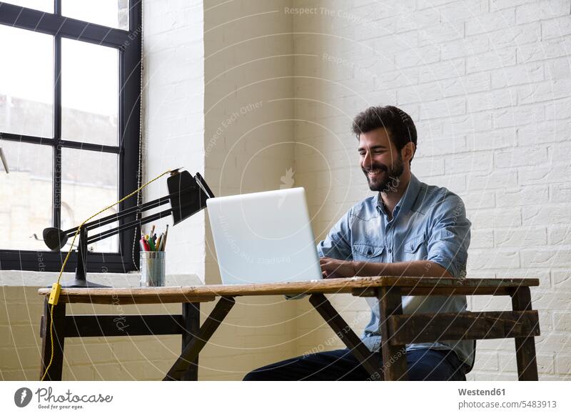 Lächelnder Mann am Schreibtisch mit Laptop Notebook Laptops Notebooks Männer männlich Computer Rechner Erwachsener erwachsen Mensch Menschen Leute People