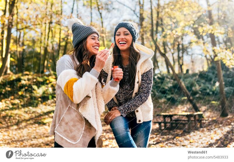 Zwei schöne Frauen amüsieren sich mit Seifenblasen in einem herbstlichen Wald Freundinnen Spaß Spass Späße spassig Spässe spaßig Herbst Forst Wälder weiblich