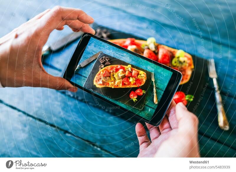 Nahaufnahme der Hände einer Frau, die ein Foto mit einer Vielzahl von Früchten in einer Papaya serviert Fotos Smartphone iPhone Smartphones Handy Mobiltelefon