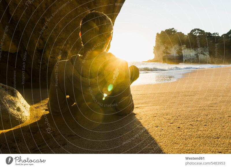Neuseeland, Wanganui, Rückenansicht eines Mannes, der am Strand liegt und den Sonnenaufgang betrachtet liegen liegend Sonnenaufgänge Männer männlich Beach