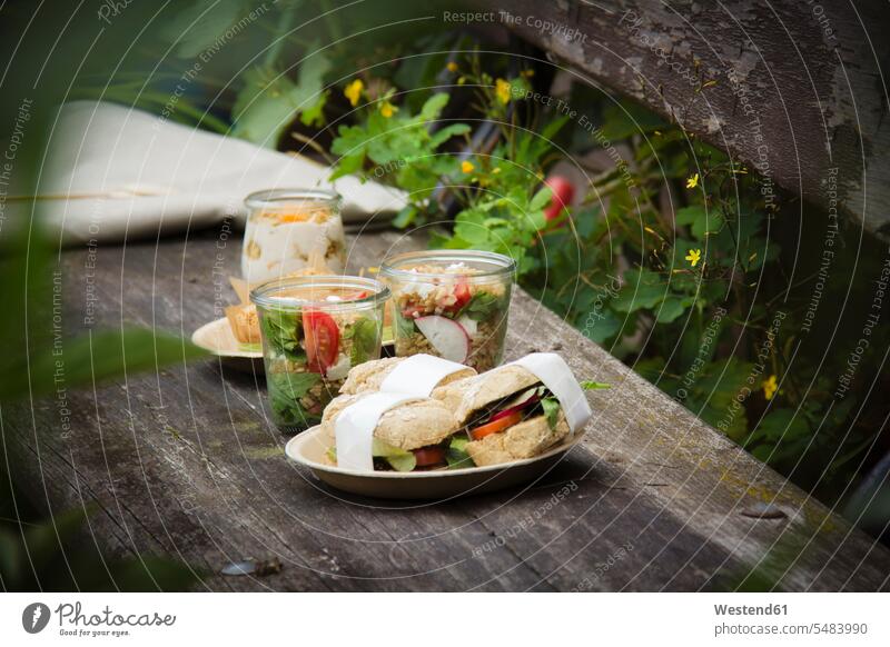 Picknick mit vegetarischen Snacks auf der Bank Imbiss Zwischenmahlzeit Glas Gläser Holzbank Holzbänke Holzbaenke Natur picknicken Außenaufnahme draußen