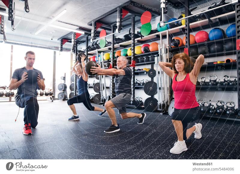 Gruppe fitter Senioren mit Personal Trainer im Fitnessstudio beim Training mit Medizinbällen trainieren alte ältere Fitnessclubs Fitnessstudios Turnhalle