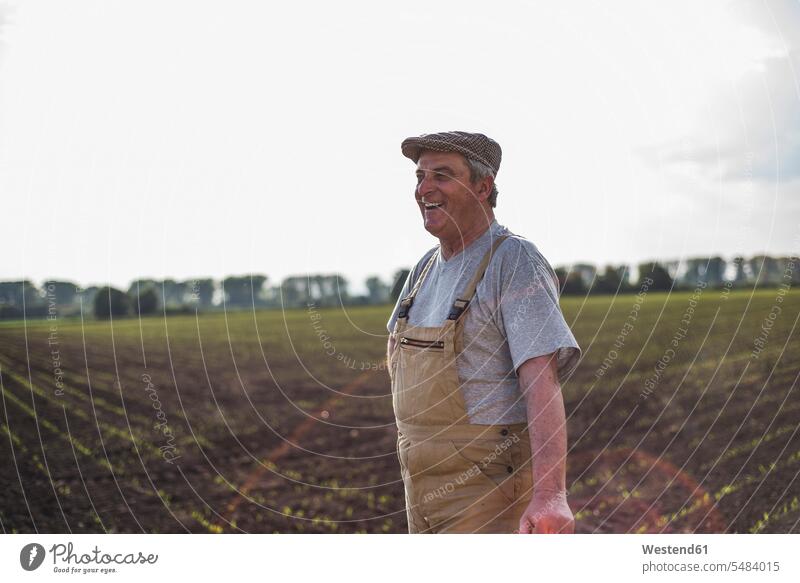 Lächelnder Landwirt steht an einem Feld lächeln Bauer Landwirte Bauern Felder Landwirtschaft Mann Männer männlich Erwachsener erwachsen Mensch Menschen Leute