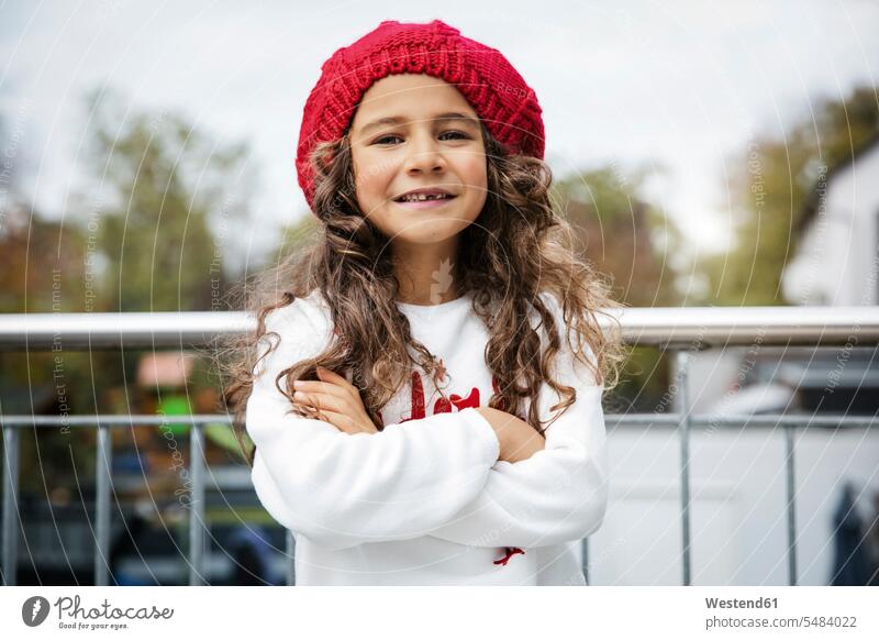Porträt eines lächelnden kleinen Mädchens mit Zahnlücke und rotem Wollhut Zahnlücken weiblich Portrait Porträts Portraits Wollmütze Wollmützen Strickmütze