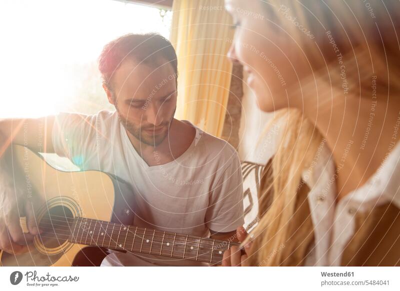 Mann spielt zu Hause Gitarre, während seine Freundin ihm zusieht musizieren Musik machen Männer männlich Erwachsener erwachsen Mensch Menschen Leute People