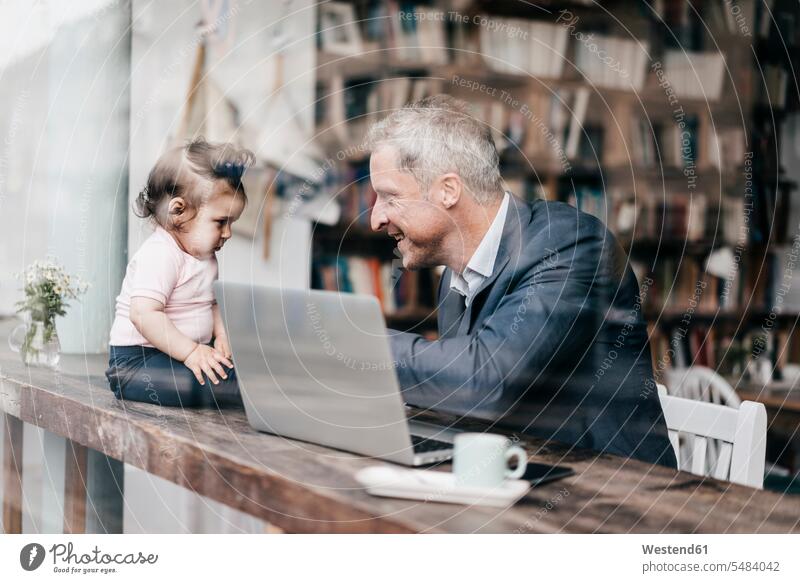 Geschäftsmann mit kleiner Tochter arbeitet am Laptop im Café spielen Notebook Laptops Notebooks sitzen sitzend sitzt Vater Papas Väter Vati Vatis Papis arbeiten