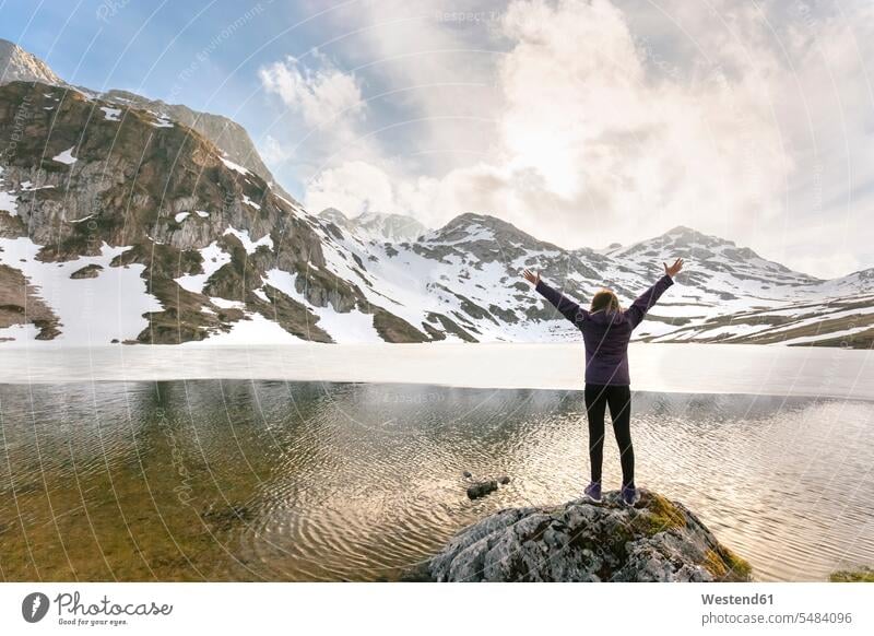 Spanien, Asturien, Somiedo, Frau steht mit erhobenen Armen am Bergsee Wanderer weiblich Frauen glücklich Glück glücklich sein glücklichsein wandern Wanderung