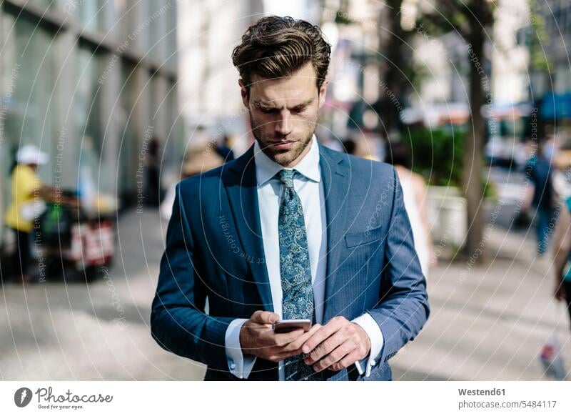 Gutaussehender Geschäftsmann zu Fuß in Manhattan, mit Mobiltelefon attraktiv schoen gut aussehend schön Attraktivität gutaussehend hübsch Pendler lesen Lektüre