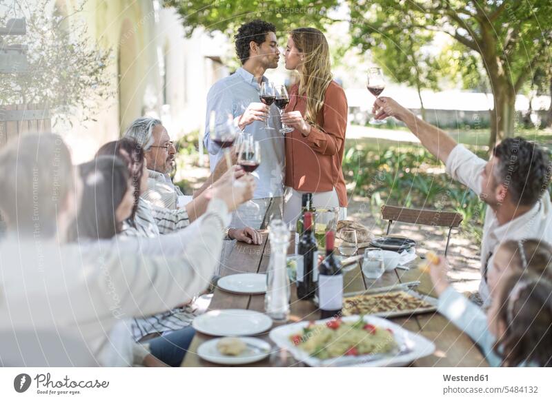 Pärchen küsst sich beim Mittagessen im Garten mit Rotwein Rotweine Gruppe Gruppe von Menschen Menschengruppe Wein Weine feiern küssen Küsse Kuss Familie