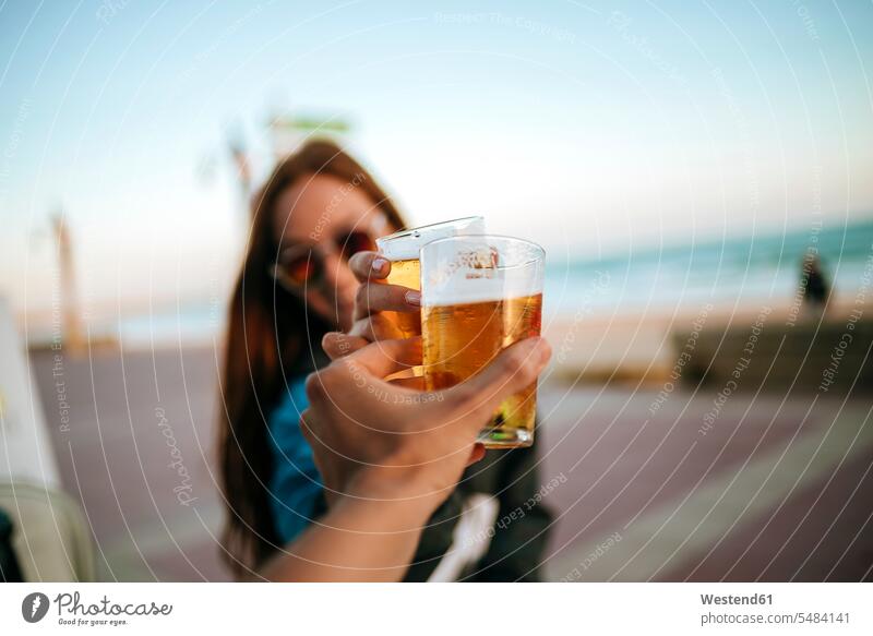 Klirrende Biergläser am Meer Glas Trinkgläser Gläser Trinkglas trinken anstoßen zuprosten anstossen lächeln Geschirr Alkohol Alkoholische Getraenke