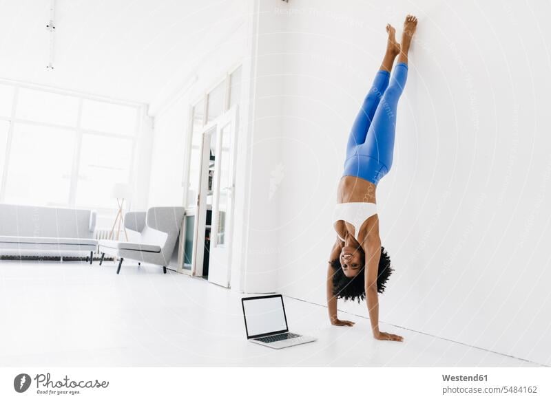 Junge Frau praktiziert Yoga mit Laptop an ihrer Seite üben ausüben Übung trainieren Training Online fit weiblich Frauen Notebook Laptops Notebooks lernen