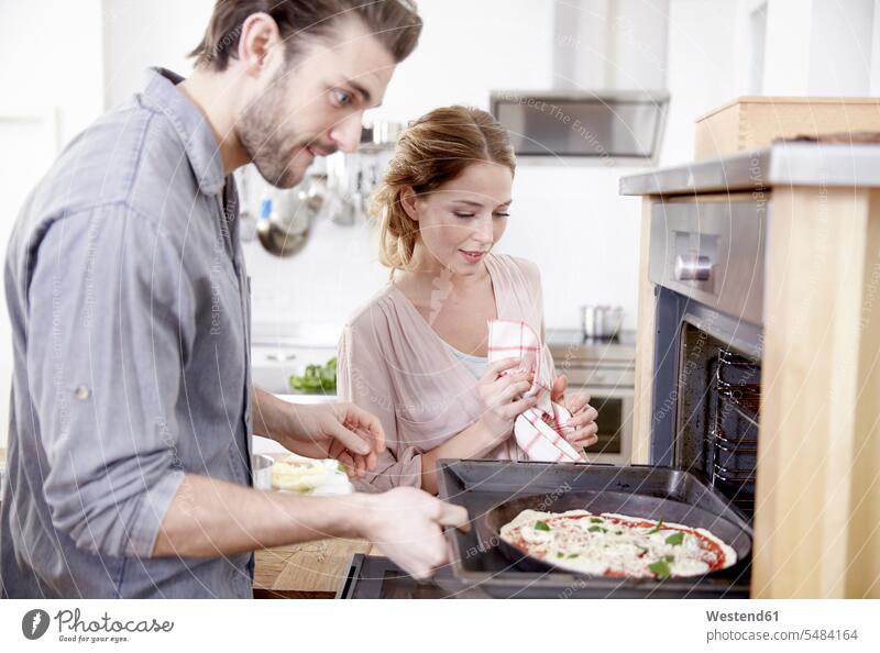 Ehepaar schiebt Pizza in den Ofen Europäer Kaukasier Europäisch kaukasisch zubereiten kochen Essen zubereiten zwei Personen 2 2 Personen 2 Menschen