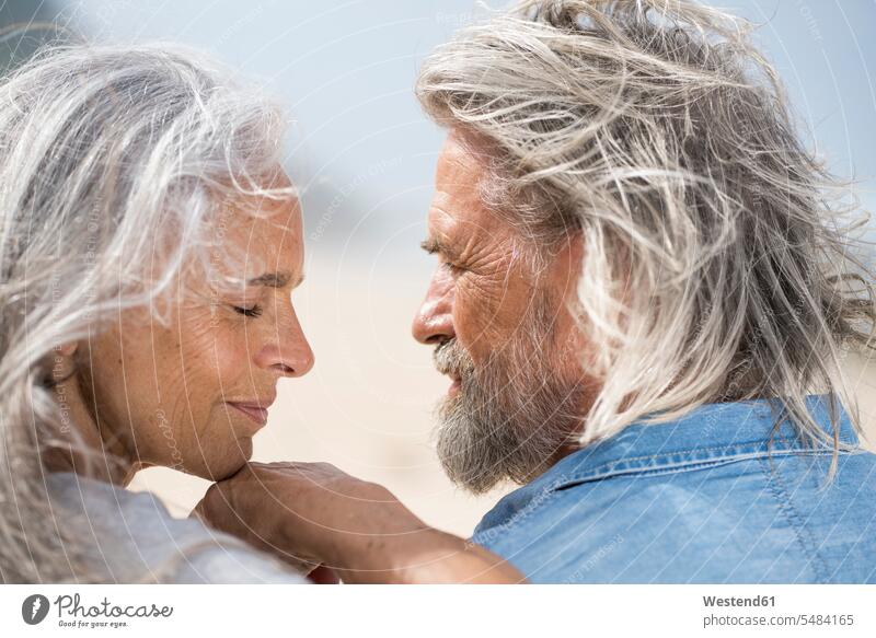 Liebevolles älteres Ehepaar, das sich vor dem Meer in die Augen schaut Strand Beach Straende Strände Beaches Urlaub Ferien attraktiv schoen gut aussehend schön