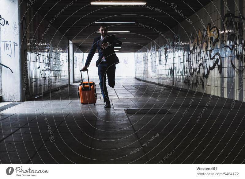 Geschäftsmann auf Geschäftsreise mit Rollgepäck unterwegs Tunnel Businessmann Businessmänner Geschäftsmänner Koffer jung laufen rennen Verkehrswesen