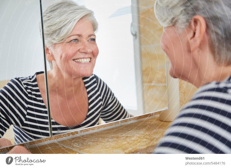 Porträt einer lächelnden Frau, die sich selbst im Badezimmerspiegel betrachtet Spiegel weiblich Frauen Erwachsener erwachsen Mensch Menschen Leute People