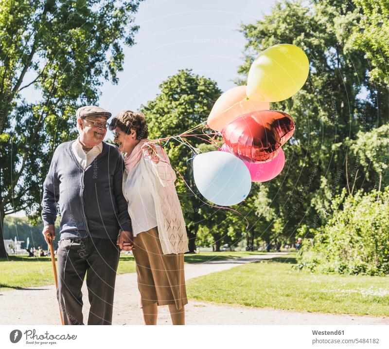 Glückliches älteres Ehepaar mit Luftballons in einem Park Seniorenpaar älteres Paar Seniorenpaare ältere Paare Seniorenpärchen Ballons Luftballone