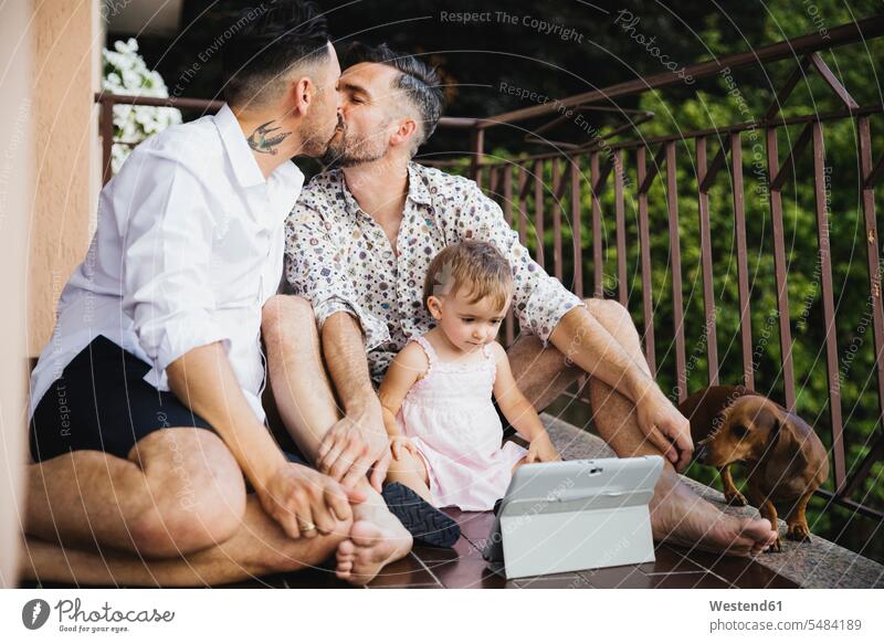 Schwules Paar küsst sich mit Tochter und Hund auf dem Balkon schwul Homosexueller Mann Homosexuelle Maenner Schwuler Homosexuelle Männer küssen Küsse Kuss