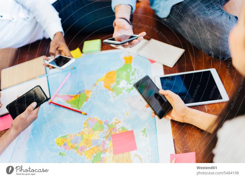 Gruppe von Freunden mit Smartphones plant gemeinsamen Urlaub Karte Karten reisen verreisen Handy Mobiltelefon Handies Handys Mobiltelefone iPhone Freundschaft