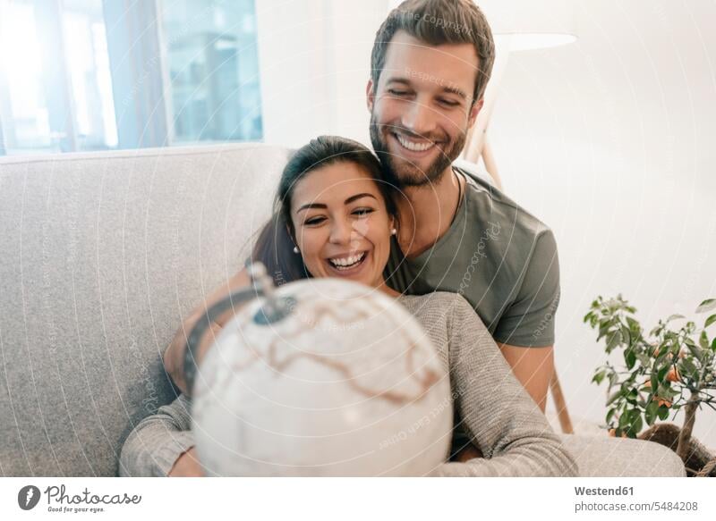 Glückliches Paar zu Hause auf dem Sofa mit Blick auf den Globus entspannt entspanntheit relaxt Pärchen Paare Partnerschaft ansehen glücklich glücklich sein