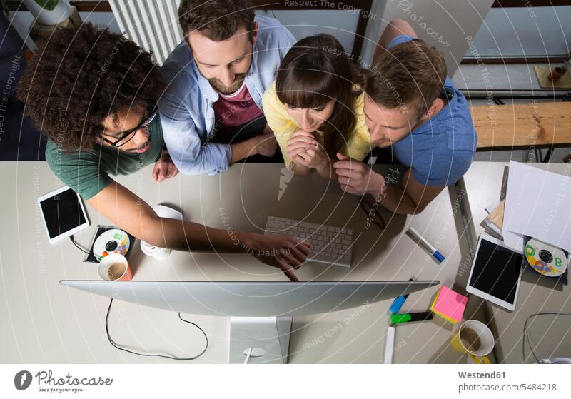 Team von Kreativen, die um einen Computerbildschirm sitzen Freiberufler freiberuflich freie Berufe Kleinunternehmen Kleingewerbe Kleinbetrieb Teilen Sharing