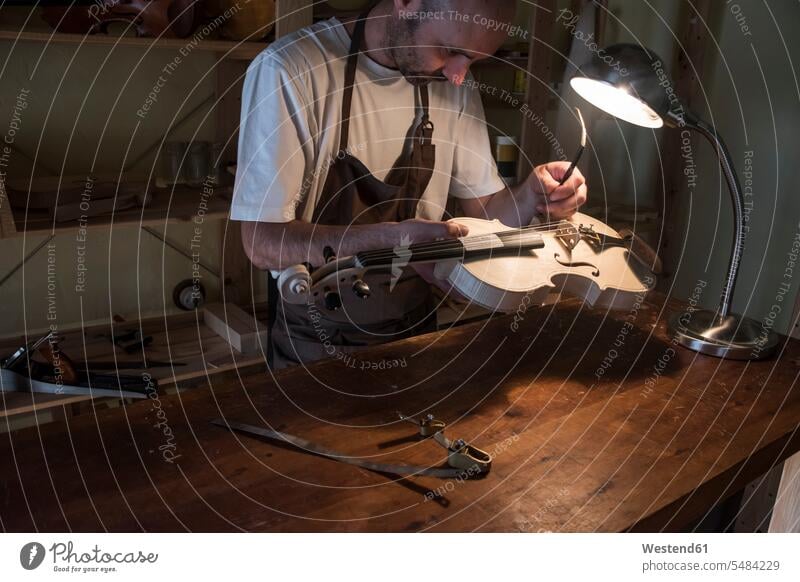 Geigenbauer beim Einstellen des Stimmstocks einer Geige in seiner Werkstatt Mann Männer männlich Violine Violinen Werkstätte Werkstaette Werkstaetten