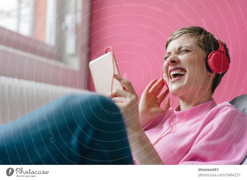 Schreiende Frau mit Handy und Kopfhörern beim Musikhören Mobiltelefon Handies Handys Mobiltelefone schreien rufen rufend schreiend hoeren weiblich Frauen