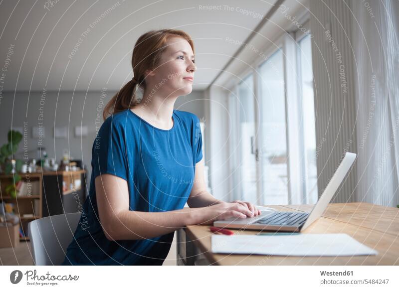 Junge Frau sitzt mit Laptop am Tisch Europäer Kaukasier Europäisch kaukasisch Laptop benutzen Laptop benützen WLan Wireless Lan W-Lan Wifi Notebook Laptops