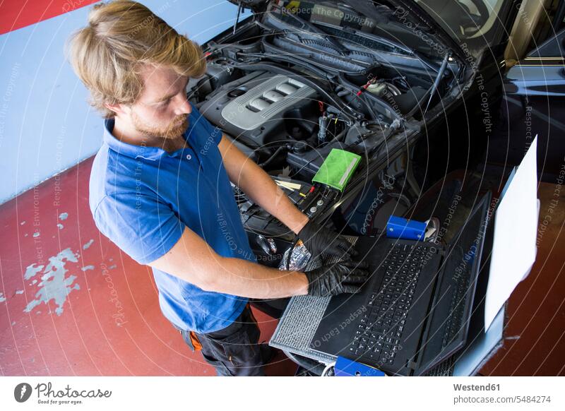 Mechaniker, der einen Computer benutzt, während er ein Auto repariert Monteur Rechner Elektronik Autowerkstatt PKW Werkstatt KFZ Werkstatt Kfz-Werkstatt