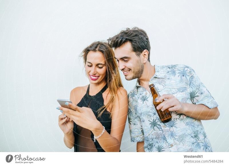 Junges Paar mit Bier und Handy im Freien glücklich Glück glücklich sein glücklichsein Pärchen Paare Partnerschaft Mobiltelefon Handies Handys Mobiltelefone