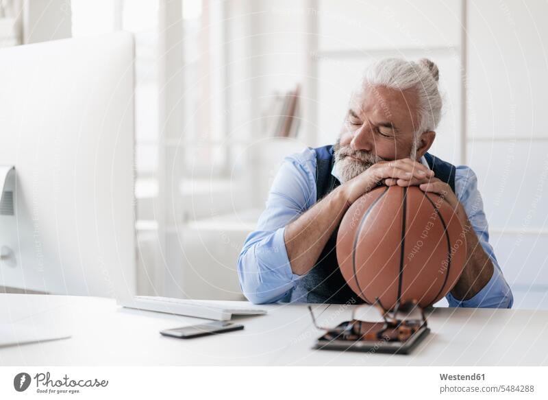 Entspannter reifer Mann am Schreibtisch mit Basketball Portrait Porträts Portraits schlafen schlafend entspannt entspanntheit relaxt Männer männlich Sport