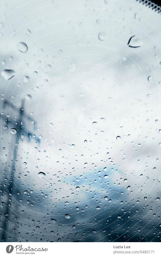 Blick aus dem Autofenster, Regentropfen und ein Strommast in Unschärfe Fenster Glas Scheibe Himmel blau dunkelblau stürmisch Herbst herbstlich Wetter Tropfen
