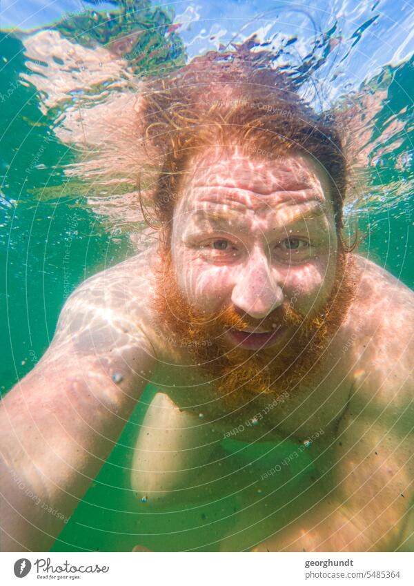 Mann mit rotem Haar und rotem Bart taucht in einem Süßwassersee. Die Augen offen. See unterwasser tauchen schwimmen baden spiegelung rothaarig mann taucher