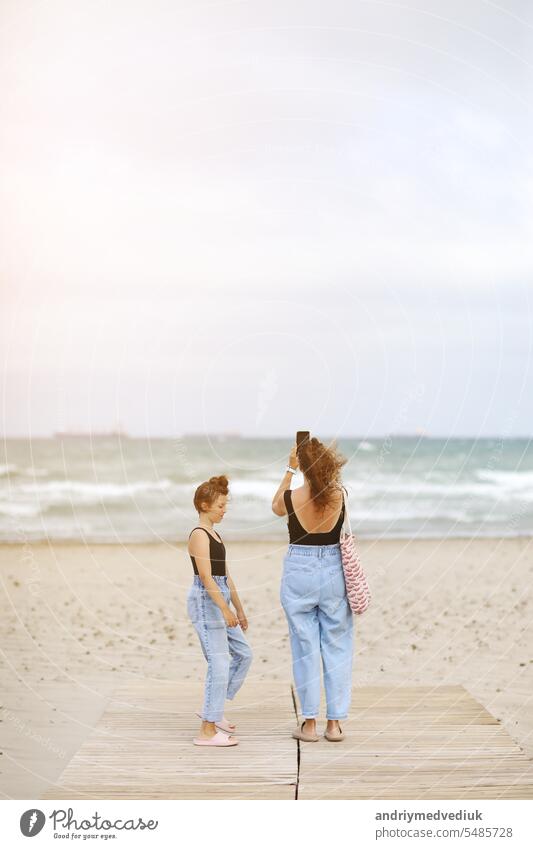Glückliche Familie im Strandurlaub. Rückenansicht von Mutter und kleine Tochter gehen zusammen und halten die Hände am Strand. Mama und Kind Mädchen Kind genießen und Spaß haben in den Sommerferien
