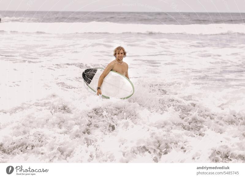 junge fit Surfer Mann mit Surfbrett läuft in Ozean oder Meer mit großen Wellen zum Surfen. Konzept der extremen Sport, Fitness, Freiheit, Glück, neue moderne Leben. Sport Reiseziel.