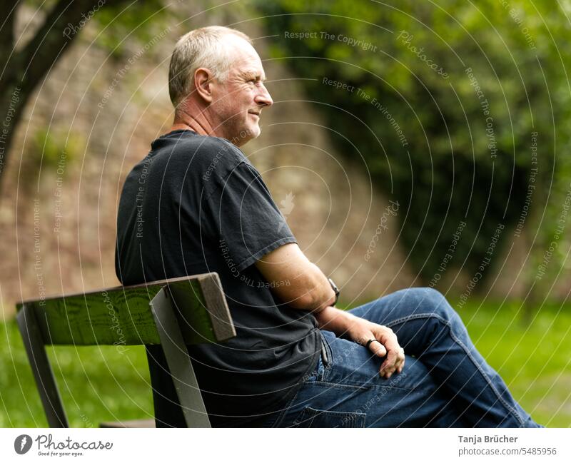 Mann mittleren Alters sitzt auf einer Parkbank mit Blick in die Ferne Ein Mann allein reifer Mann Erwachsener Mann mittleren Alters 50 - 55 Jahre Sehnsucht