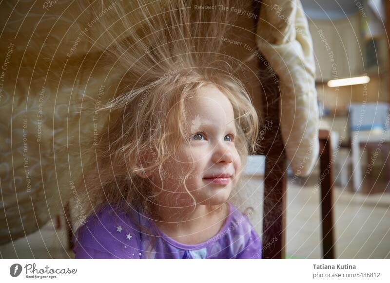 Ein Kind spielt zu Hause in einem aus einer Decke gebauten Haus. statisch Behaarung Haare aufstellen Kindheit elektrisch fluffig Elektrizität Wissenschaft