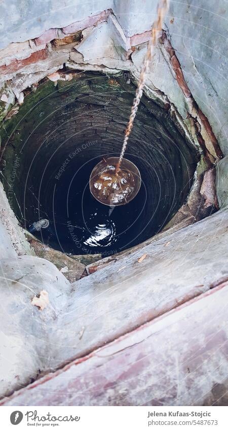 Alter Ziehbrunnen mit gefülltem Wassereimer von Oben gesehen. Brunnen Altertum Bauernhof Landwirtschaft Trinkwasser Erfrischung Außenaufnahme Wassergewinnung