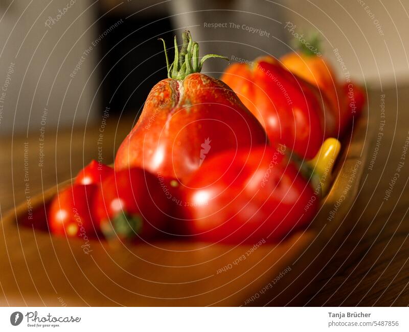 Nahaufnahme rote und gelbe Tomaten in einer länglichen Holzschale auf Holztisch Bio-Gemüse rote Tomaten Vegane Ernährung frische Ernte viele Tomaten
