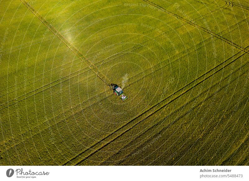 Ein Traktor fährt durch ein Getreidefeld und hinterlässt Spuren Kornfeld Feld verschiedene Traktorspuren grün Deutschland Luftaufnahme Gerät Feldfrüchte