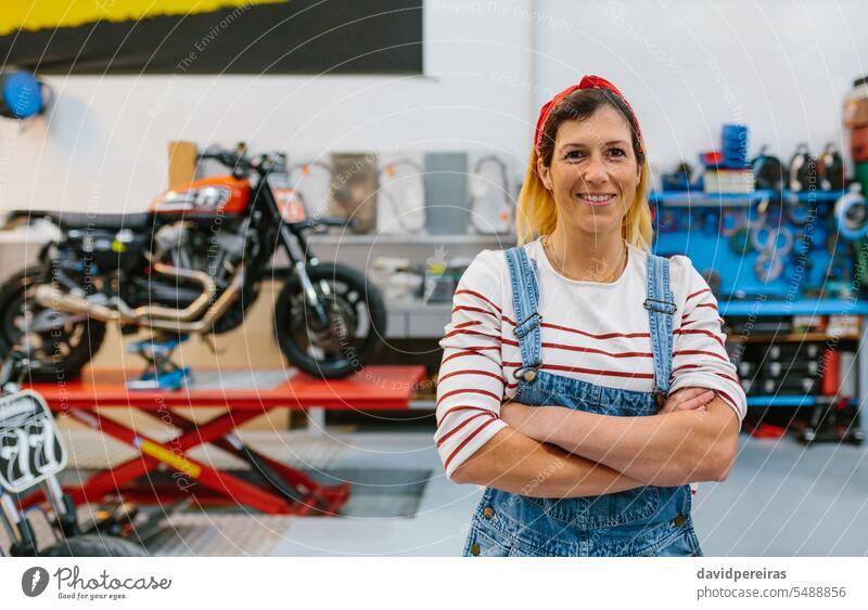 Porträt einer Mechanikerin auf einer Motorradfabrik Frau Lächeln Fröhlichkeit Glück Blick Fotokamera Fabrik Podest Beruf Arbeiter Garage Werkstatt Job