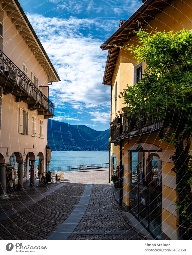 Blick durch eine Straße auf den Lago Maggiore Lago maggiore see strasse Häuser Stadt See Wasser Außenaufnahme Berge u. Gebirge Landschaft