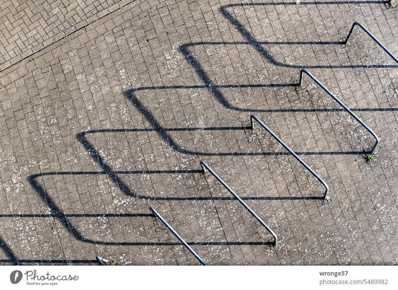 Fahrradanlehnbügel und lange Schatten aus der Vogelperspektive Fahrradbügel Anlehnbügel Draufsicht flacher Sonnenstand abstrakt Abstraktion Pflasterstraße