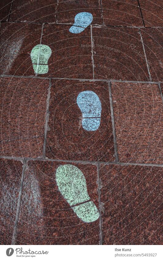 Grüne und blaue Fussabdrücke auf Pflastersteinen Fußspur grün Spuren Innenstadt Steinfliesen Steinboden