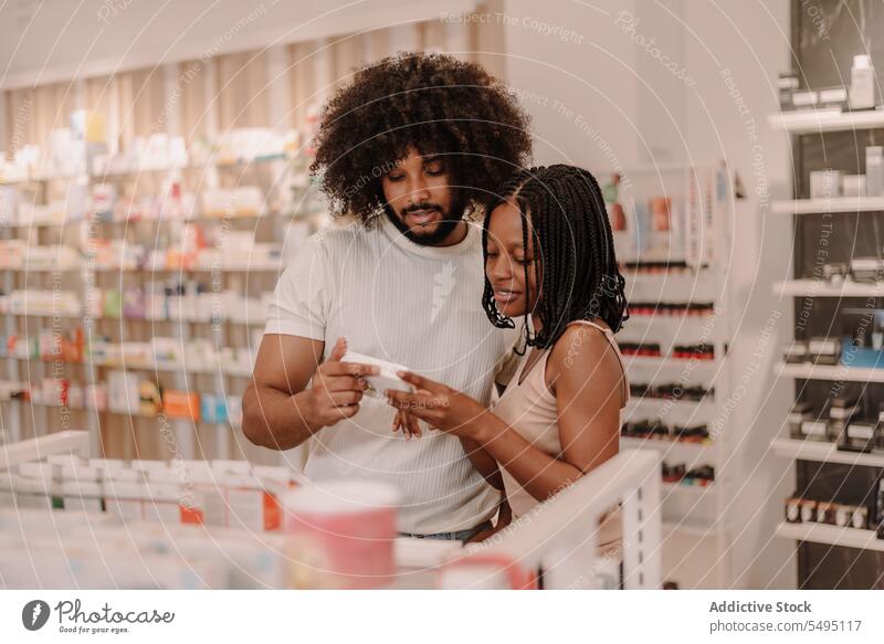 Schwarzes Paar liest Informationen auf einer Medikamentenpackung in einer Drogerie Freund Freundin Apotheke kaufen Laden Mann Frau lesen Medizin Paket