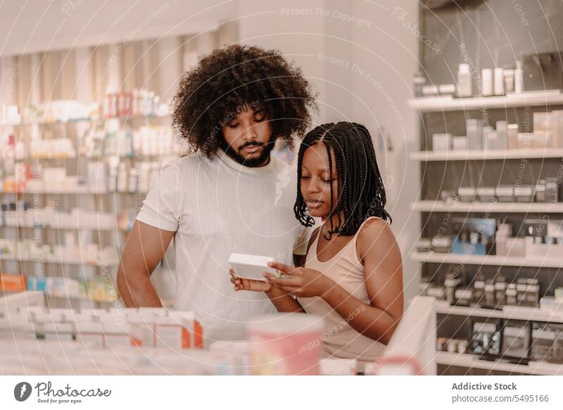 Schwarzes Paar liest Informationen auf einer Medikamentenpackung in einer Drogerie Freund Freundin Apotheke kaufen Laden Mann Frau lesen Medizin Paket