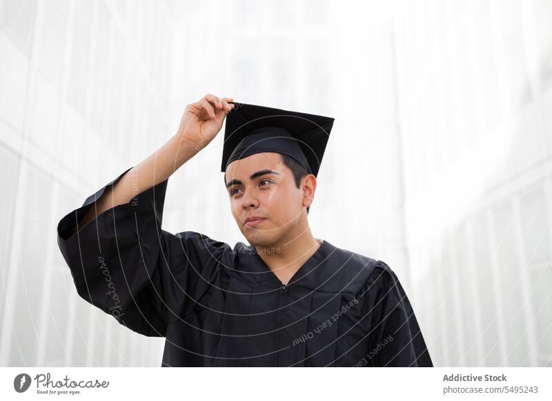 Mann in Graduierungsrobe und Kappe auf weißem Hintergrund, der wegschaut jung Abschluss Kleid Verschlussdeckel selbstbewusst Schüler Errungenschaft Porträt