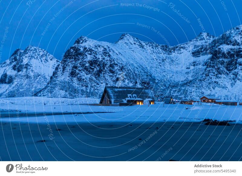 Altes Dorf in der Nähe von verschneiten Bergen unter Himmel Berge u. Gebirge Haus Insel Winter Schnee malerisch lofoten Landschaft Natur Norwegen Gebäude kalt